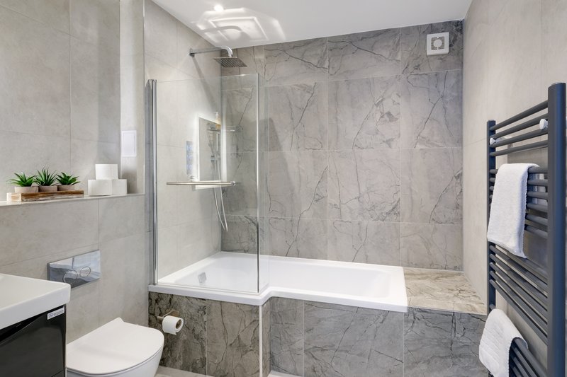 Modern bathroom with walk-in shower, marble tiles, toilet, and heated towel rail