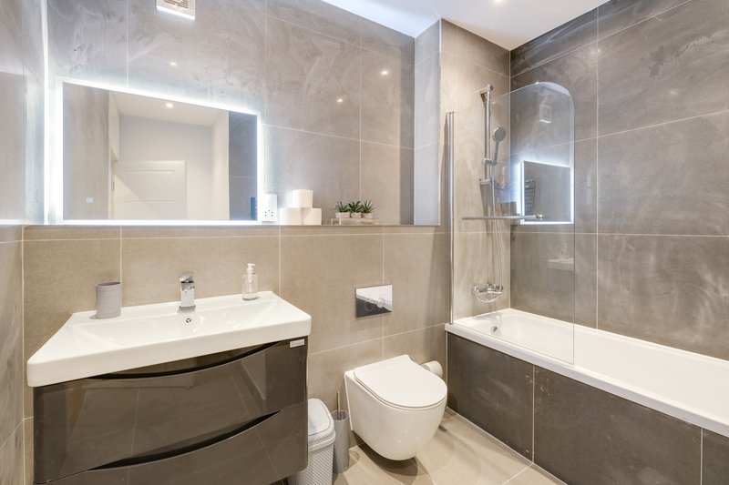 Modern bathroom with sink, toilet, bathtub, shower enclosure and illuminated mirror