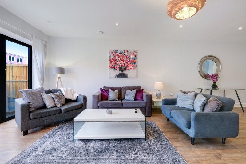 Spacious living room with three sofas, white coffee table, artwork, and wooden flooring