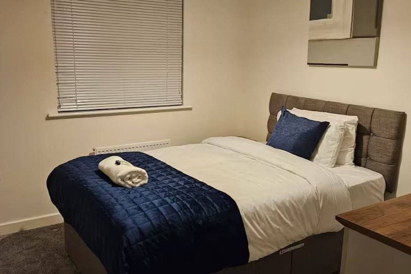 Bedroom with double bed, navy bedding, wooden headboard and side table