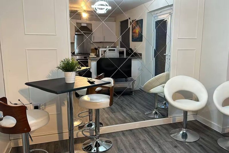 Modern open-plan accommodation with black desk, white bar stools, and contemporary seating area