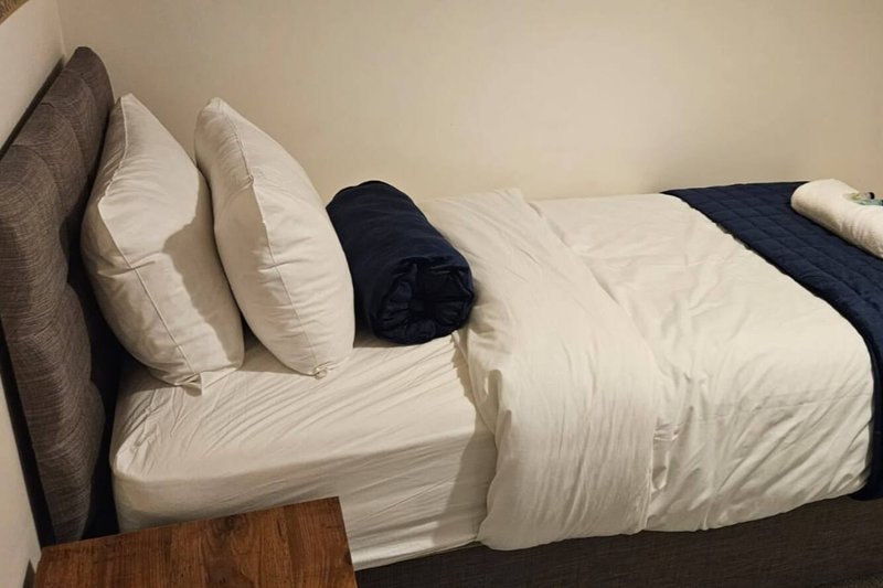 Bedroom with neatly made bed, white pillows, navy bedding, and wooden headboard