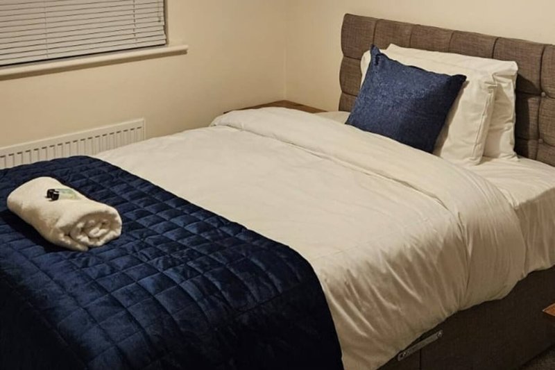 Bedroom with double bed, navy bedding, white pillows, and dark wooden headboard