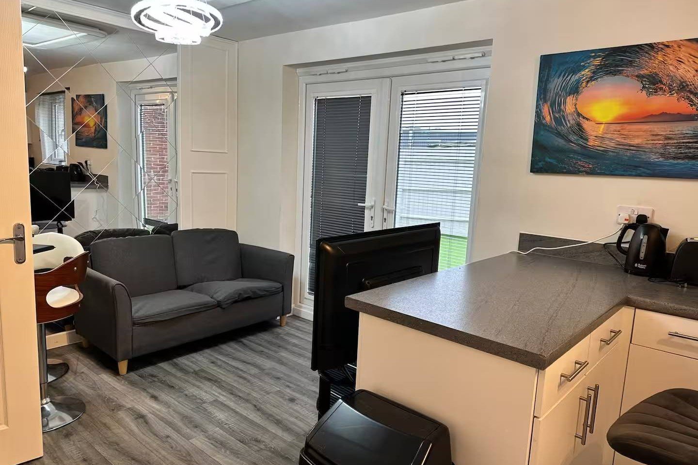 Open-plan living space with black sofa, kitchen island, and patio doors leading outside