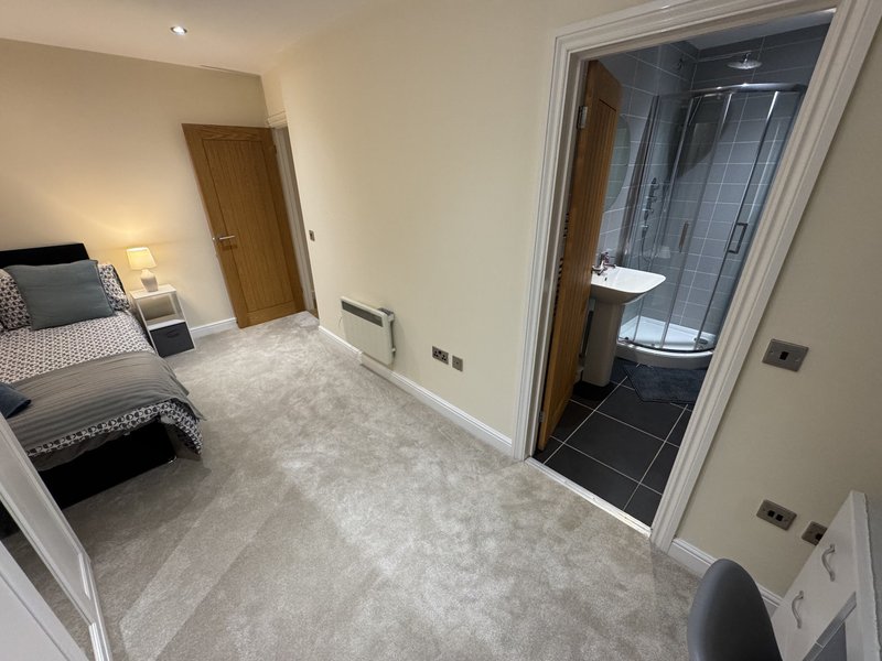 Modern bedroom with double bed, ensuite bathroom, carpet flooring and neutral décor