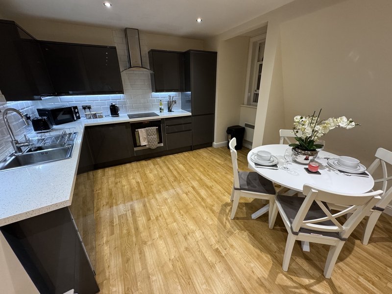 Modern kitchen-diner with black cabinetry, white countertops, wooden flooring and round dining table