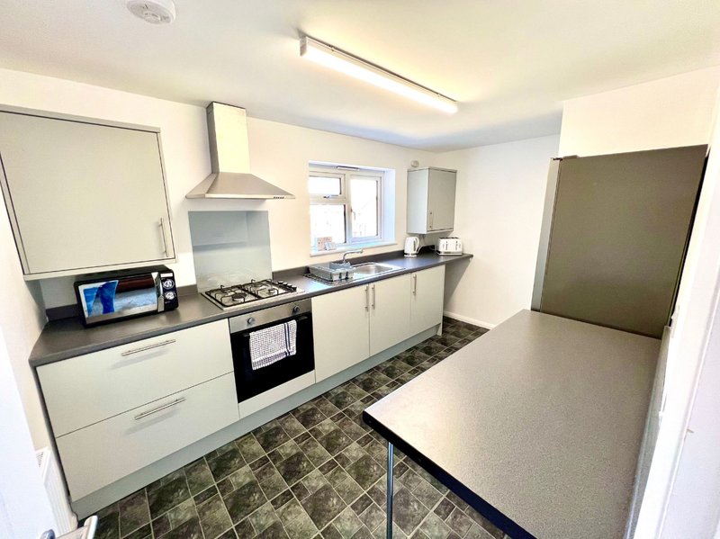 Modern kitchen with white cabinets, black countertop, gas hob and stainless steel extractor hood