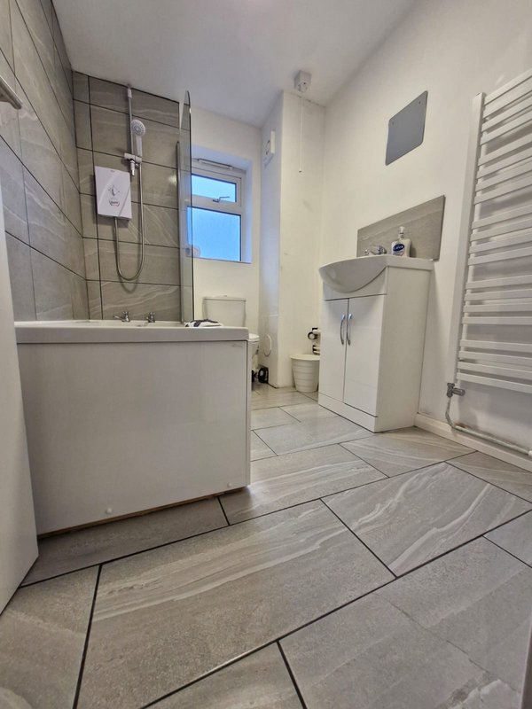 Modern bathroom with walk-in shower, white vanity, toilet, heated towel rail and window