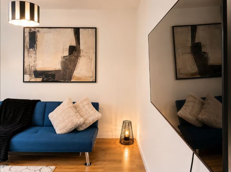 Modern living room with blue sofa, cushions, framed abstract artwork and mirror