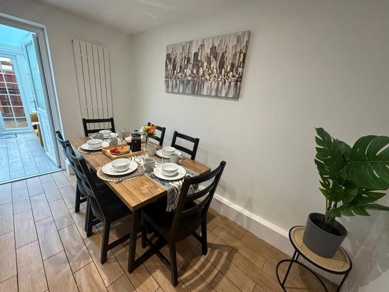 Dining room with wooden table, black chairs, place settings, wall art and potted plant
