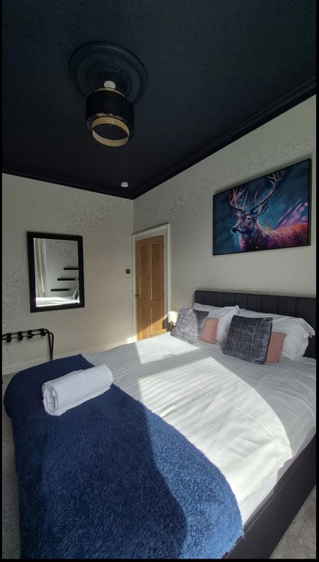 Modern bedroom with double bed, dark ceiling, white walls and framed wall art