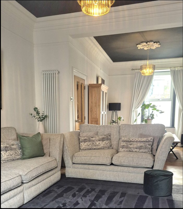 Modern living room with grey upholstered sofa, armchair, pendant lights and large windows