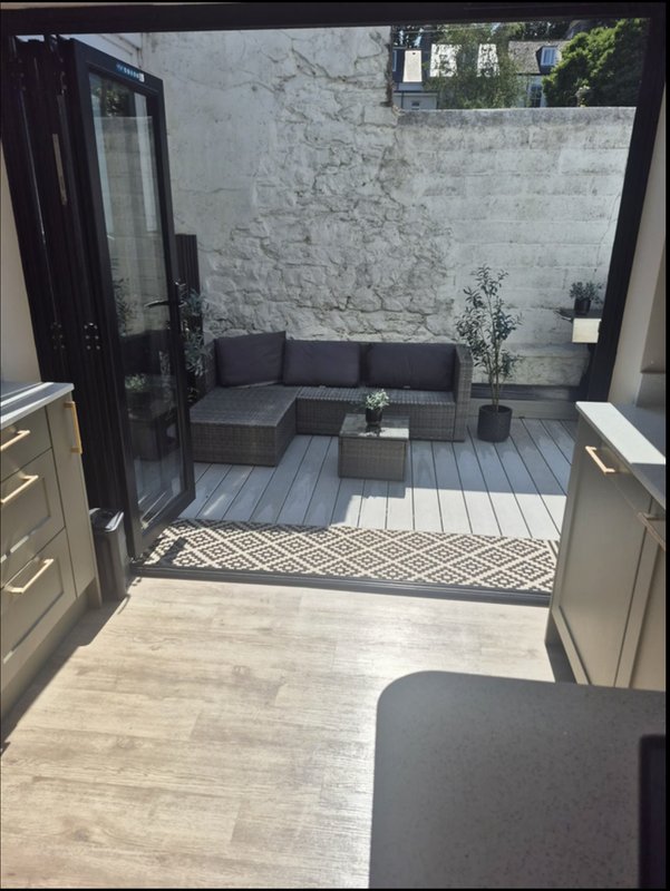 Modern kitchen opening onto outdoor patio with seating area and marble wall