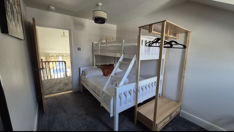 Bedroom with white metal bunk bed frame, wooden wardrobe, and mirror on wall