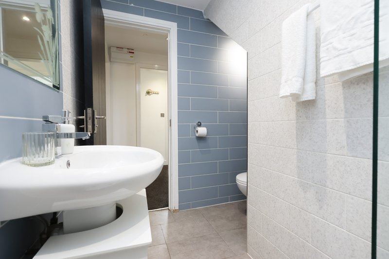 Modern bathroom with round white sink, blue and white tile walls, shower enclosure