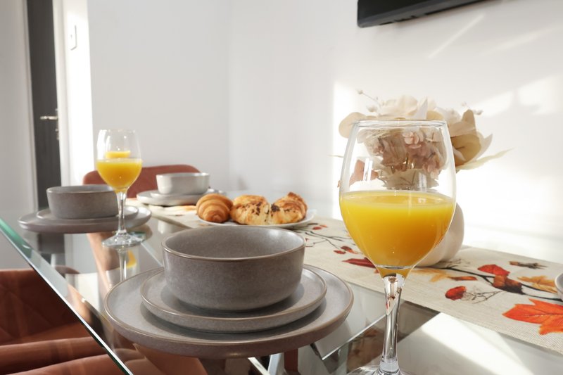 Dining table set with plates, orange juice glasses, croissants and breakfast items