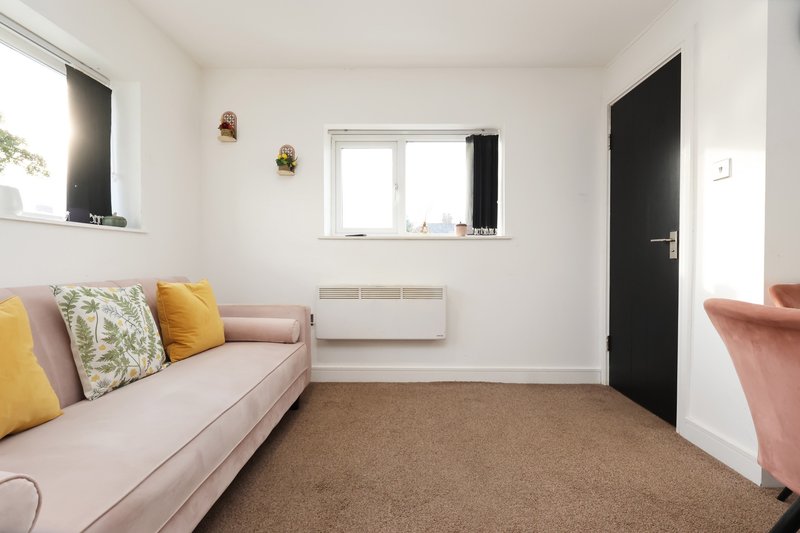 Bright living room with pink sofa, decorative cushions, brown carpet and window