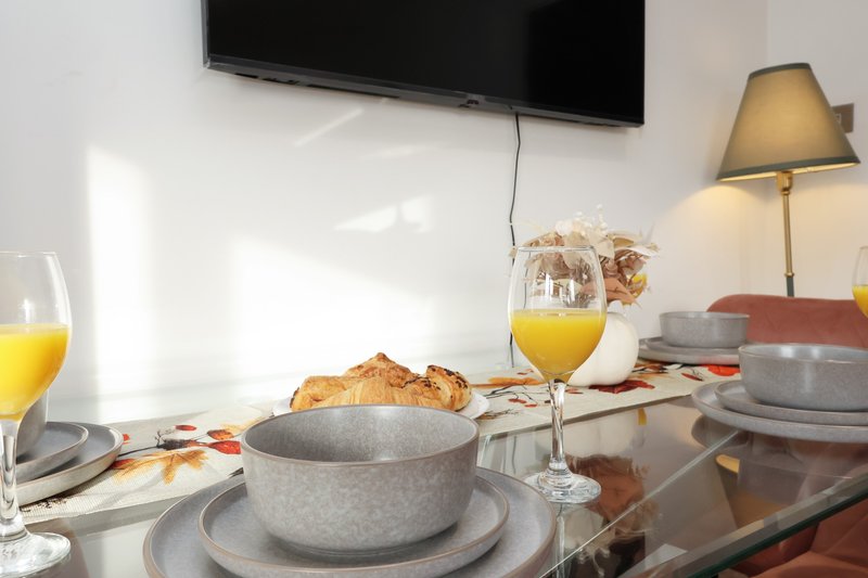 Dining table set with gray bowls, glasses of juice, bread, and table lamp