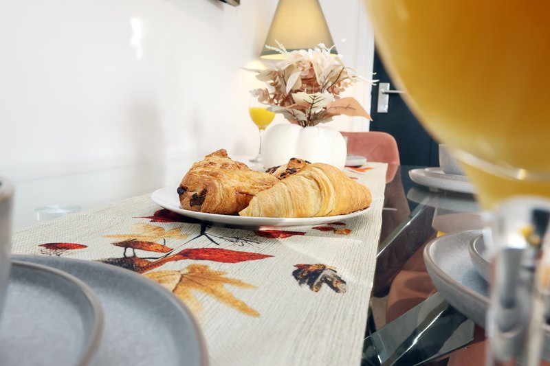 Breakfast table with croissants, plates, wine bottle and table settings
