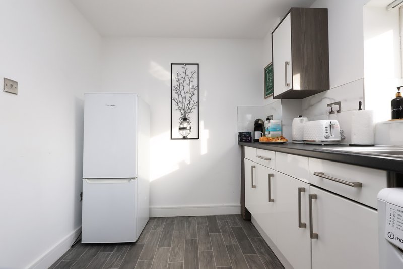 Modern kitchen with white appliances, dark wood flooring, wall-mounted cabinets and countertop