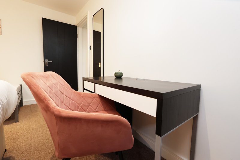 Bedroom with terracotta armchair, black desk, mirror and dark door