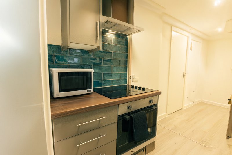 Modern kitchen with teal tile backsplash, stainless steel oven, microwave and wooden countertop
