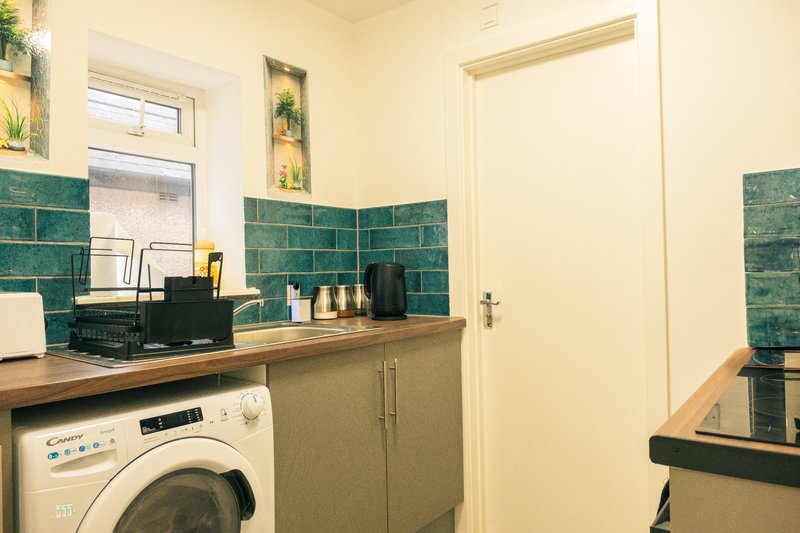 Utility room with washing machine, wooden counter, green tile splashback and window