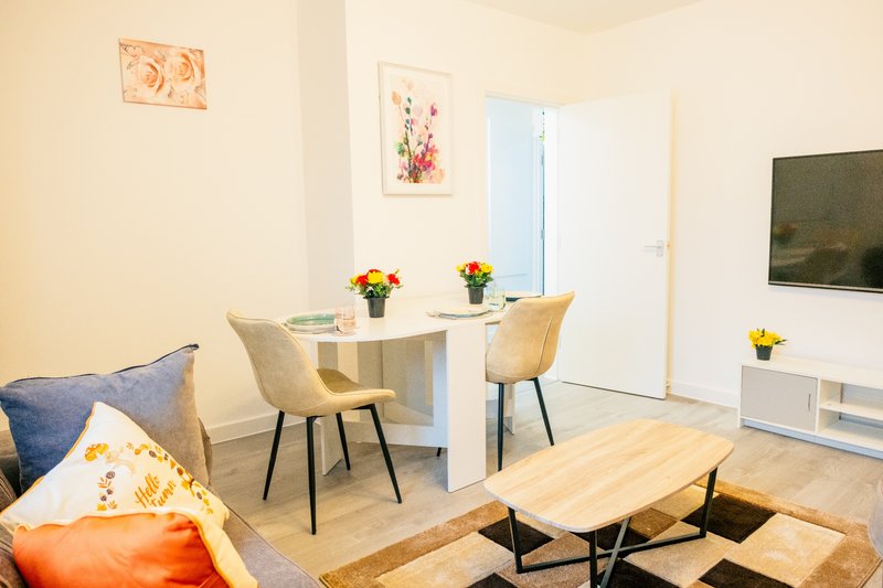 Open-plan living room with dining area, sofa, TV, and wooden coffee table