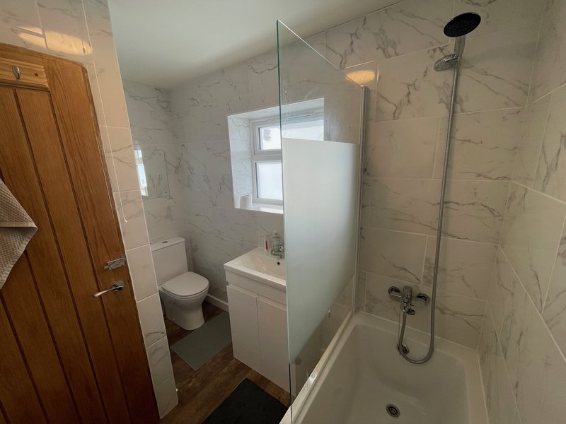 Bathroom 1 - Modern bathroom with marble-effect tiling, white vanity, toilet, shower enclosure and window