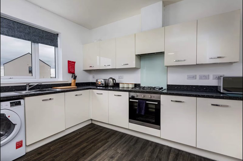 Modern kitchen with cream cabinets, black worktops, integrated appliances and window