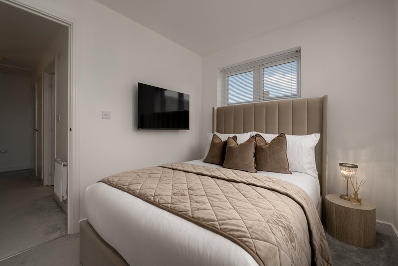Modern bedroom with double bed, wall-mounted TV, upholstered headboard and window