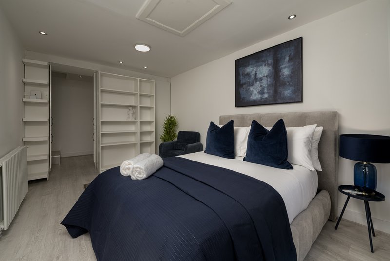 Modern bedroom with double bed, navy bedding, white pillows, wall art and built-in wardrobes