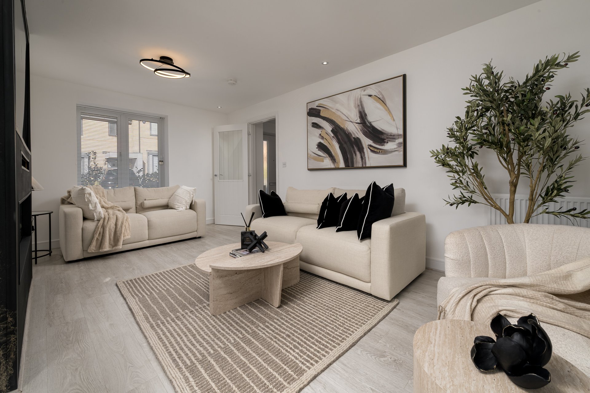 Bright modern living room with cream sofas, wooden coffee table, and indoor plant