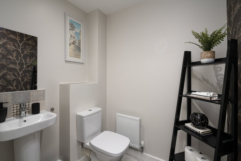 Modern bathroom with white toilet, sink, mirror and black shelving unit