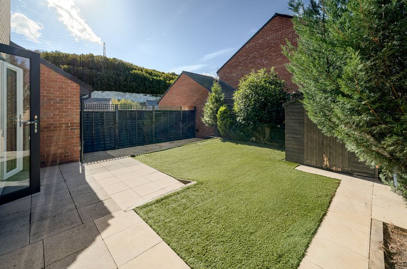 Rear garden with lawn, paved patio, wooden fence and brick property walls