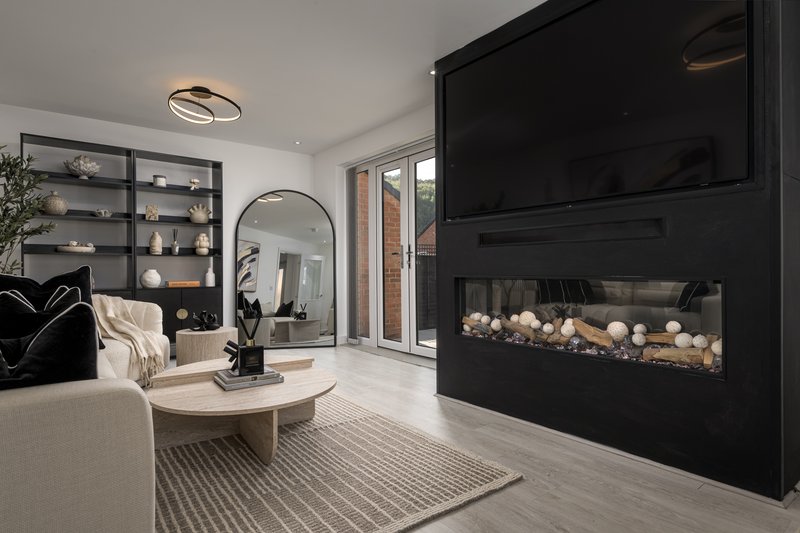 Modern living room with fireplace, cream sofa, shelving unit, and glass doors to garden