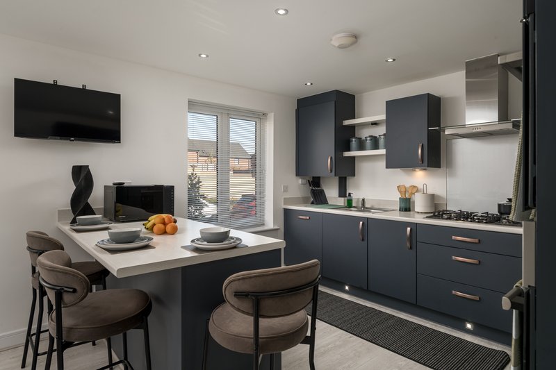 Modern kitchen with dark cabinetry, island seating, gas hob, and open-plan dining area