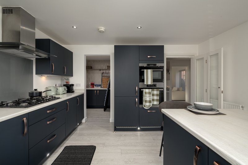 Modern kitchen with dark cabinetry, white countertops, stainless steel appliances and island