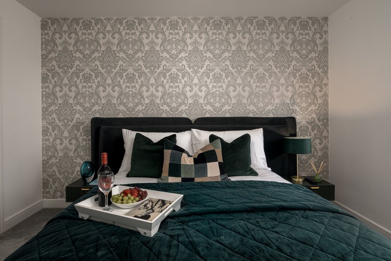 Modern bedroom with black upholstered bed, patterned wallpaper, decorative pillows and tray