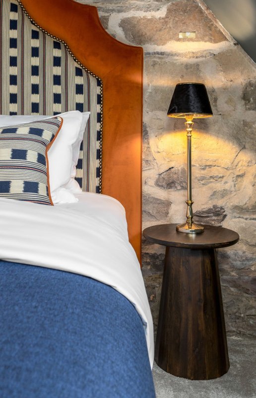 Bedroom corner with double bed, patterned headboard, bedside table and floor lamp