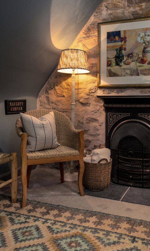 Cozy corner with wooden armchair, striped cushion, floor lamp, and fireplace