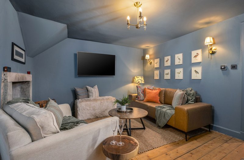 Light blue living room with cream and tan seating, wall-mounted TV, framed artwork and decorative lighting