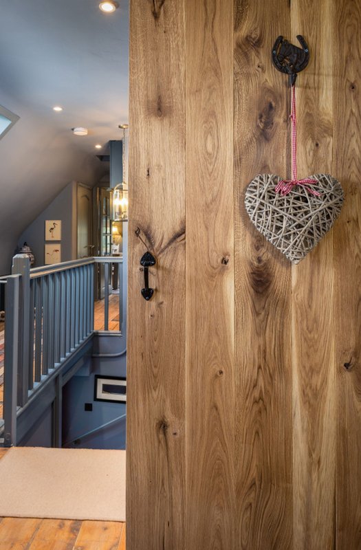 Wooden door with woven heart decoration, staircase and railing visible beyond