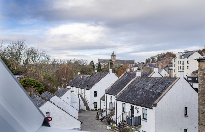 Elevated view of white-painted rural cottages with dark slate roofs and village church in background