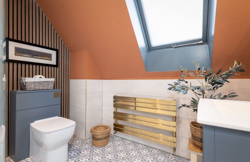 Modern bathroom with white toilet, sink, skylight window and decorative plants