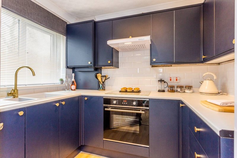 Modern kitchen with navy blue cabinetry, gold hardware, white subway tile backsplash and stainless steel appliances