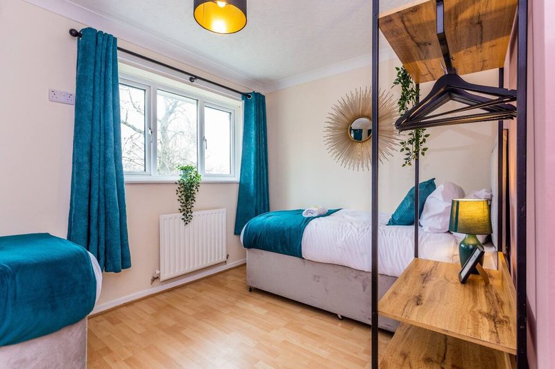 Bedroom with double bed, teal curtains, wooden floor, mirror and window