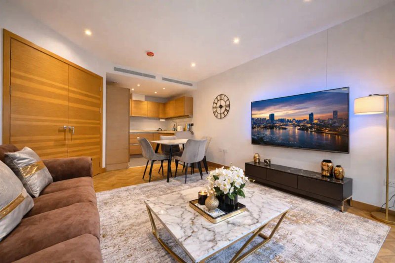 Modern studio apartment with marble coffee table, wood cabinetry, kitchenette and city skyline artwork