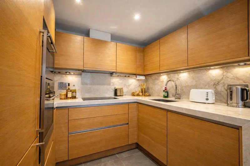 Modern kitchen with wooden cabinetry, white countertops, stainless steel appliances and recessed lighting