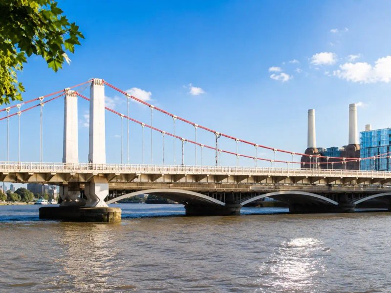 Albert Bridge spanning the River Thames with blue sky and London cityscape in background